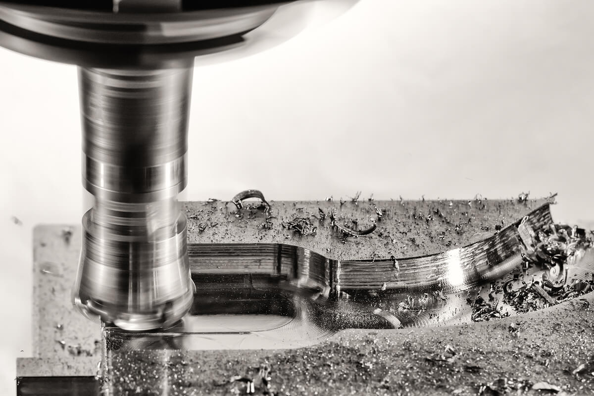 CNC milling machine cutting a metal part with metal shavings visible.
